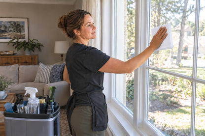 Residential cleaner wiping a home window with a folded white Krystal Klear Cloth